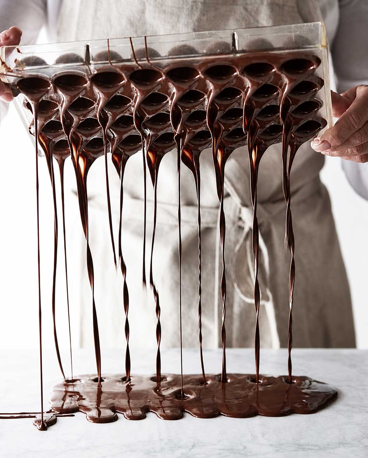 Motlle de bombons amb xocolata desfeta, exemple de tècniques de xocolata i elaboració professional de bomboneria.