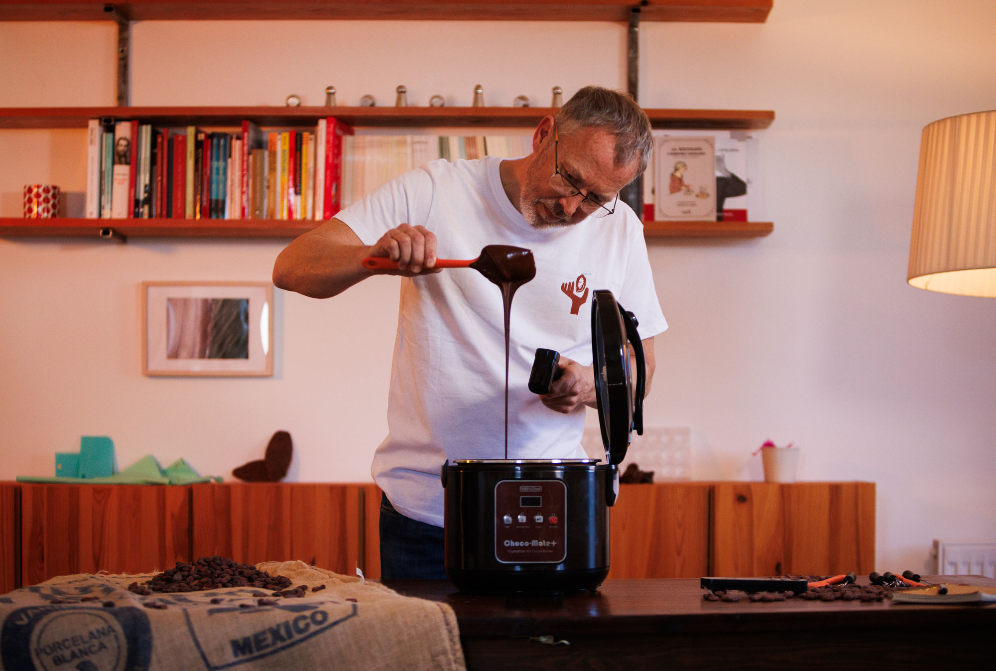 Damian Allsop treballant amb una màquina de xocolata i xocolata desfeta durant un procés d'elaboració professional.